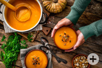 Woman serving two bowls of pumpkin soup for Thanksgiving meal